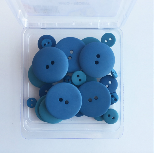 A clear plastic container filled with blue denim smoothie buttons of varying sizes, with a transparent lid on top.
Photo by JustAnotherButtonCompany.com [image_link]