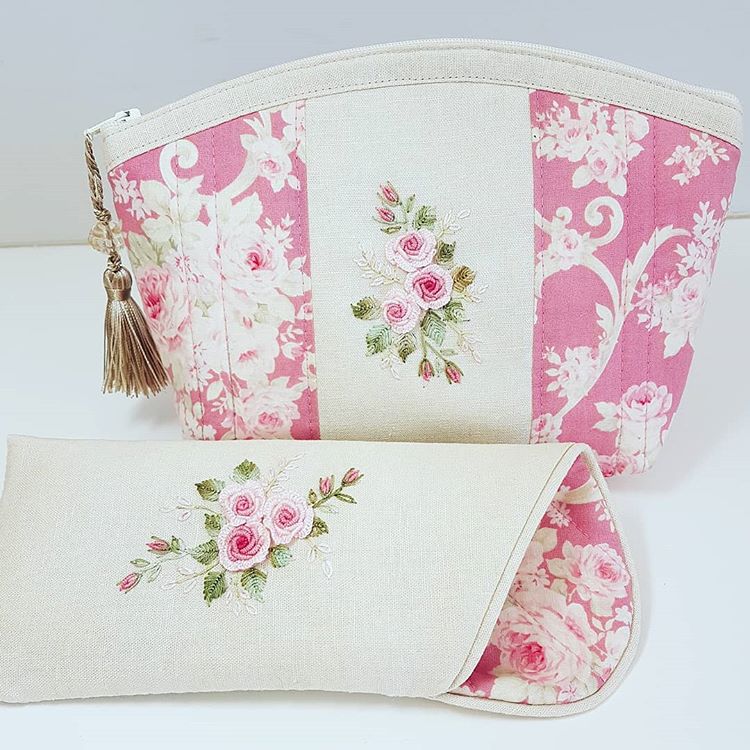 A matching fabric pouch and clutch set in a pink and cream floral patchwork design, featuring embroidered pink rose motifs and a gold tassel zipper pull.
Photo by Angela Watson [image_link]