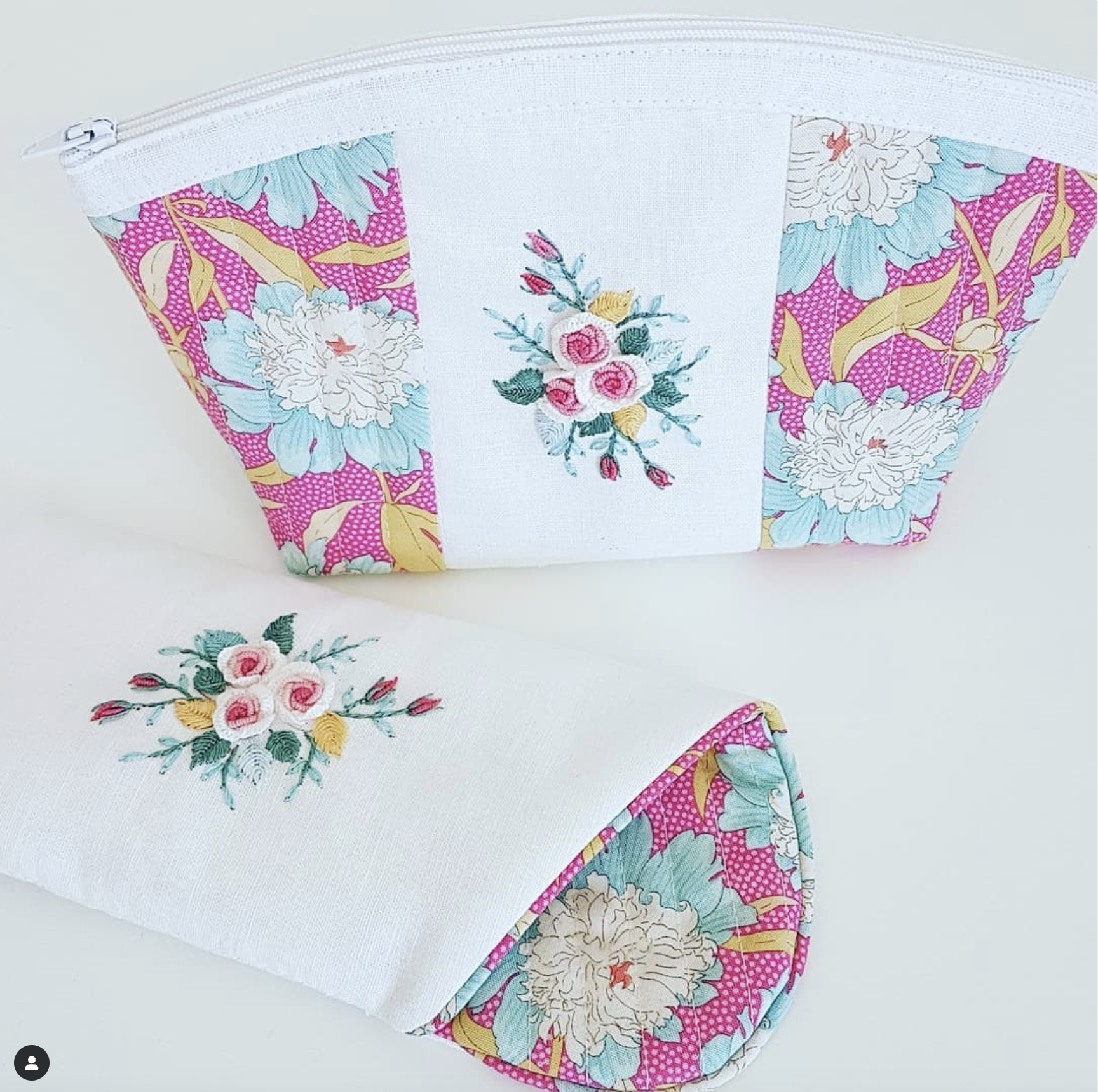 A white zippered pouch with floral fabric panels on the sides and center, shown closed from the front and folded to reveal the patterned interior. The pouch has a white zipper, white fabric body, and pink, blue, green, and yellow floral print.
Photo by Angela Watson [additional_image_link]