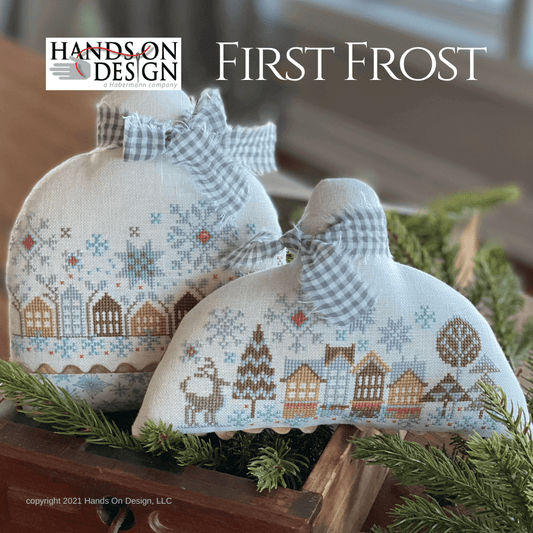 Decorative items with cross-stitch patterns on a wooden surface with greenery, featuring 'Hands On Design' branding.
Photo by HandsOnDesign.biz [image_link]