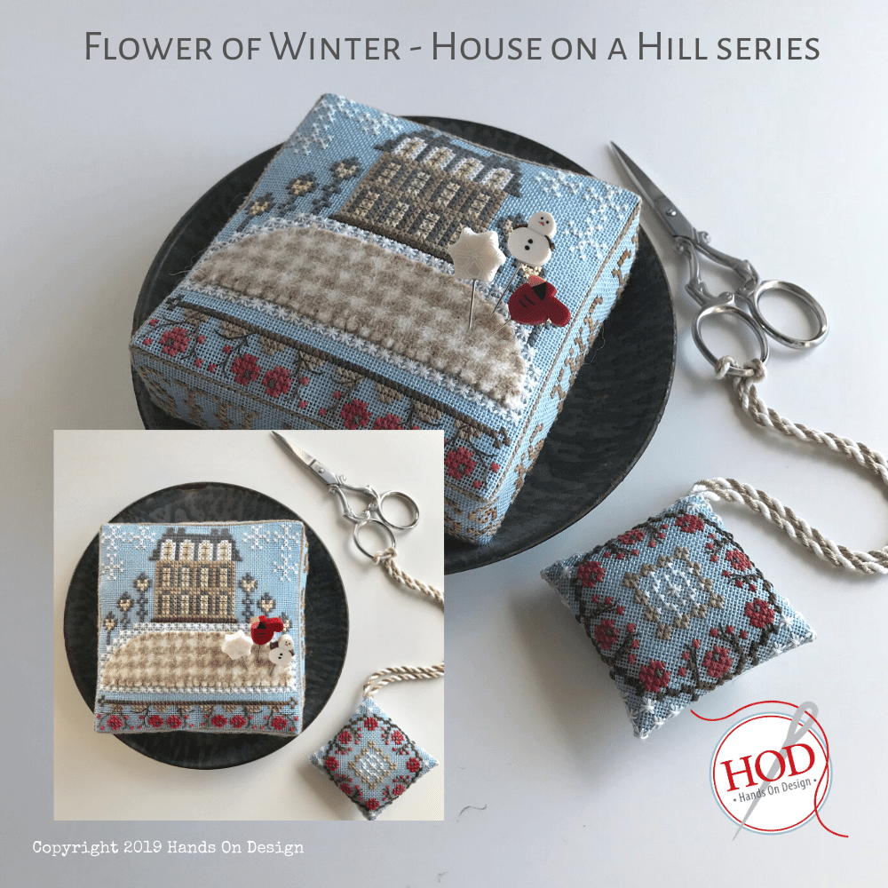 Cross stitch pincushion and fob kit, featuring a blue and multicolor design with a snowy house on a hill, part of the 'House on a Hill' series by Hands On Design.
[image_link]