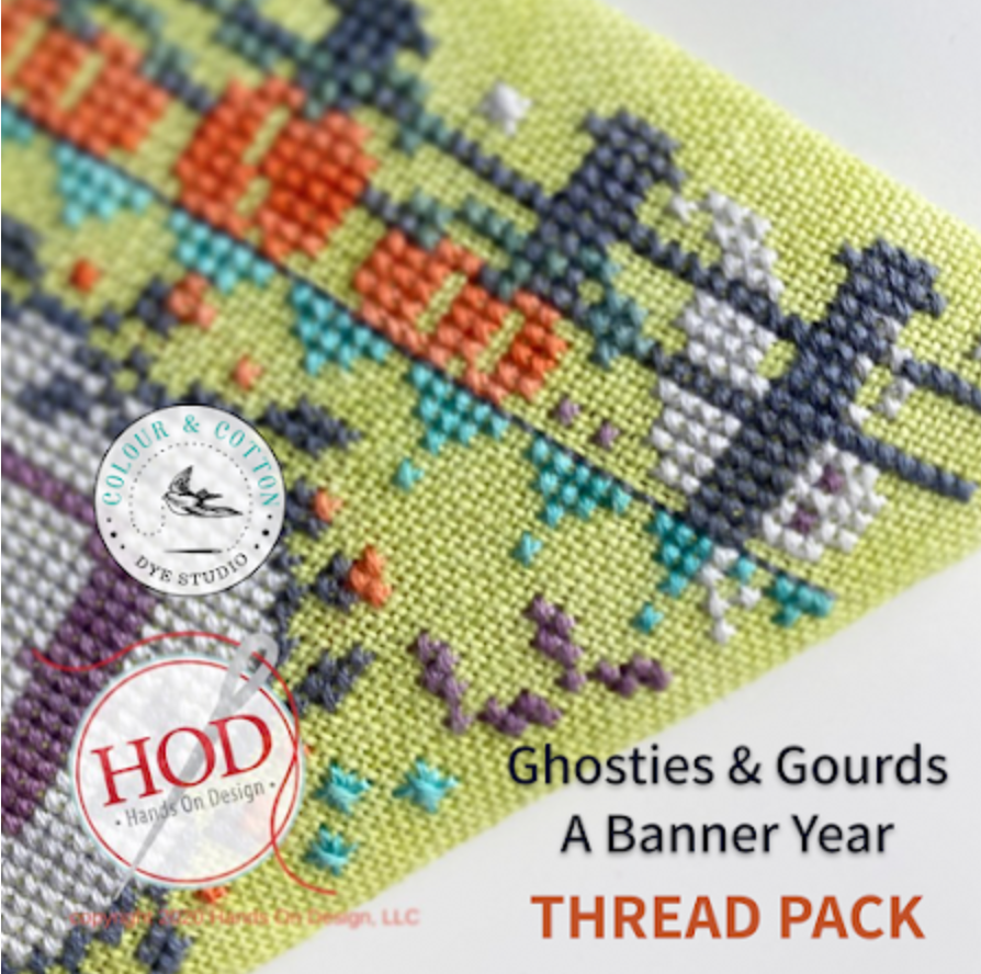 A close-up of a cross-stitch banner fabric design with the text 'Ghosties & Gourds A Banner Year THREAD PACK' and two circular logos, one reading 'Colour & Cotton Dye Studio' and the other 'HOD Hand On Design'.
[additional_image_link]