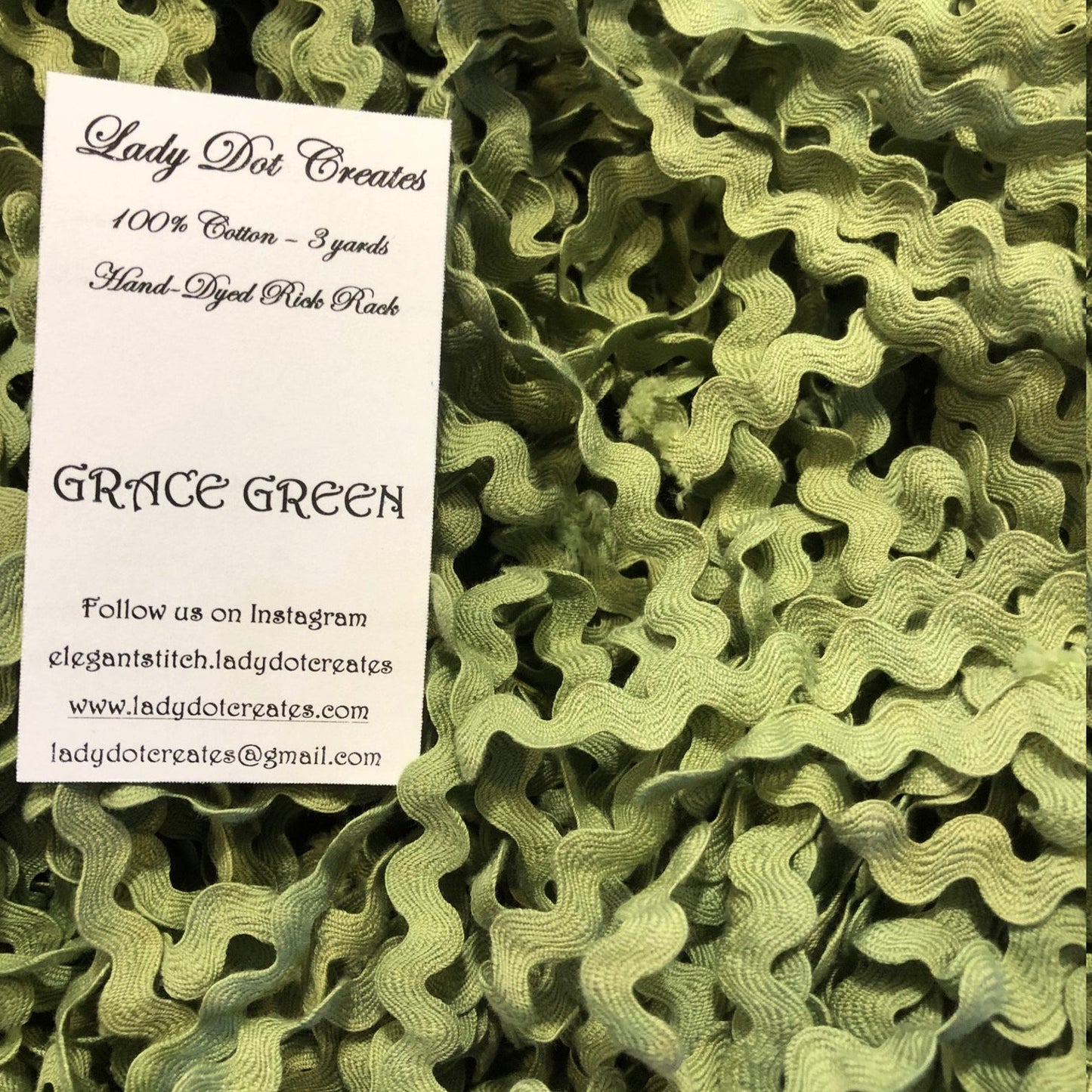 A close-up of olive green ric rac trim filling the frame, with a white paper label card reading 'Lady Dot Creates' and 'GRACE GREEN' placed on top.
[additional_image_link]