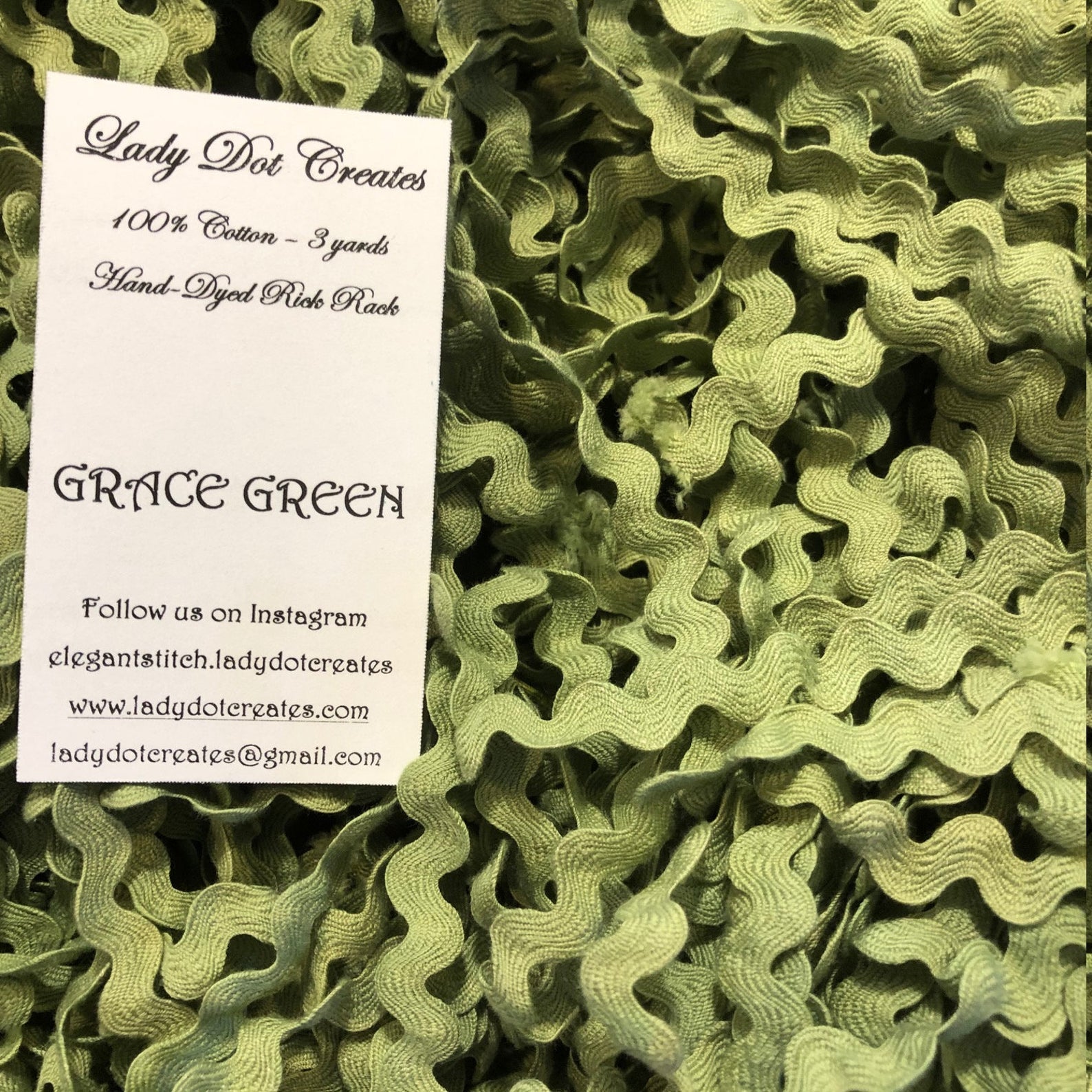A close-up of olive green ric rac trim filling the frame, with a white paper label card reading 'Lady Dot Creates' and 'GRACE GREEN' placed on top.
[additional_image_link]