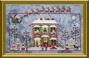A framed Christmas-themed needlepoint canvas featuring a gingerbread house, Santa Claus in a sleigh with reindeer, evergreen trees, and festive decorations, enclosed in a gold frame.
Photo by PraiseworthyStitches.com [additional_image_link]