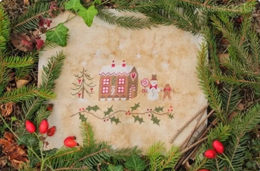 A cross stitch depicting a gingerbread house with Christmas decorations, surrounded by pine needles and red berries.
Photo by madamechantilly.com [image_link]
