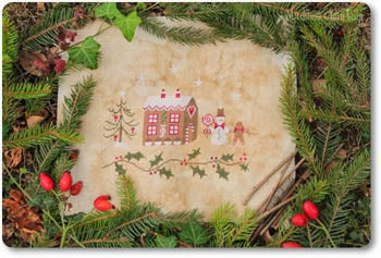 A cross stitch depicting a gingerbread house with Christmas decorations, surrounded by pine needles and red berries.
Photo by madamechantilly.com [additional_image_link]