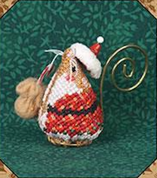 A handmade needlepoint Christmas ornament shaped like a mouse, featuring a red and white patterned body, a white fluffy hat with a red tip, a small beige fluffy accent, and a gold spiral stand, set against a dark green patterned background.
Photo by JustNan.com [image_link]