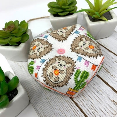 Cushion with hedgehog pattern on a wooden surface with potted plants.
Photo by Tiny Modernist [image_link]