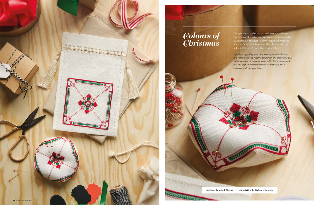 A two-panel lifestyle magazine spread showcasing a handmade embroidered Christmas pincushion and a matching drawstring pouch. The panels feature a light wood background with sewing tools, ribbon, and gift boxes, with the right panel containing the text 'Colours of Christmas'.
Photo by InspirationsStudios.com [additional_image_link]