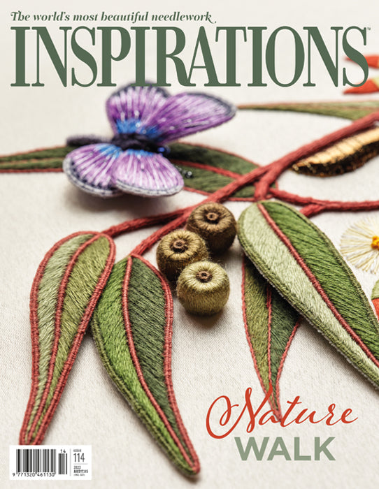 Cover of the 'INSPIRATIONS' needlework magazine featuring a close-up of an embroidered nature design with green leaves, red stitched outlines, brown acorns, and a purple flower on a light fabric background.
Photo by InspirationsStudios.com [image_link]