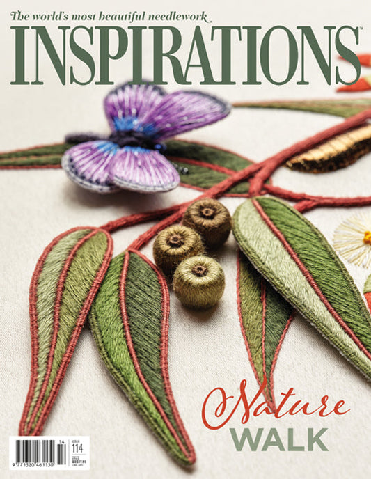 Cover of the 'INSPIRATIONS' needlework magazine featuring a close-up of an embroidered nature design with green leaves, red stitched outlines, brown acorns, and a purple flower on a light fabric background.
Photo by InspirationsStudios.com [image_link]