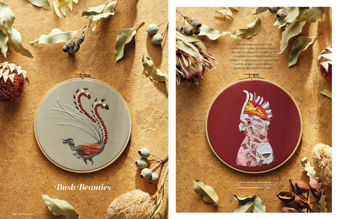 Two circular embroidery hoops displayed on a textured tan surface with dried leaves and botanicals. The left hoop shows a bird design with the text 'Bush Beauties' beneath it.
Photo by InspirationsStudios.com [additional_image_link]