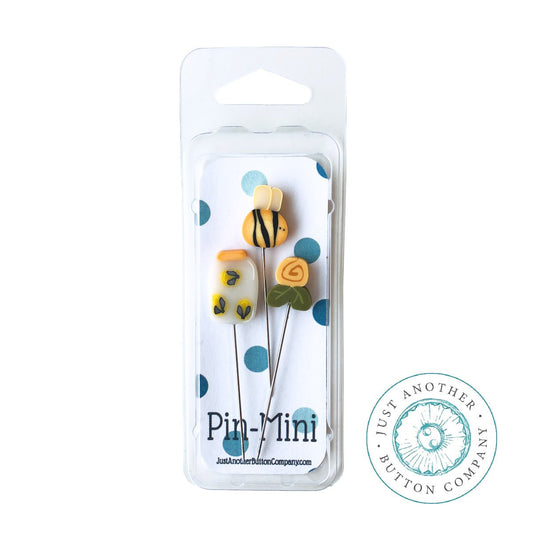 Packaging of 'It's Summer Pin Mini Limited Edition' from Just Another Button Company, displaying three decorative sewing pins with polymer clay tops designed as a bee, fireflies, and a yellow rose, along with the text indicating the product name and brand.
Photo by JustAnotherButtonCompany.com [image_link]