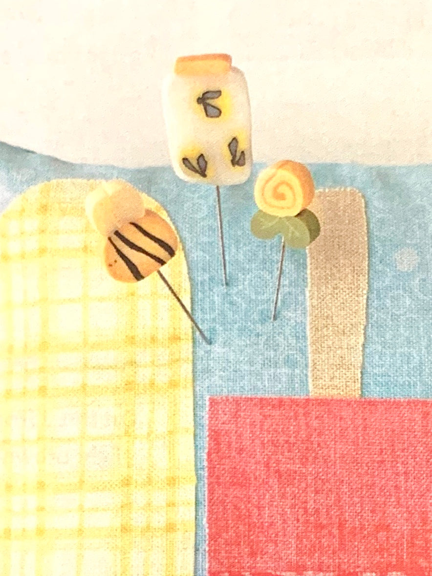 Close up of pins on the mini pinnie, a bee, a yellow rosebud and a jar with fireflies.
Photo by JustAnotherButtonCompany.com [additional_image_link]