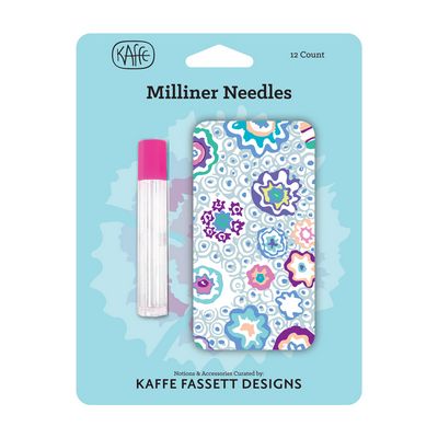 Kaffe FASSET Designs Milliner Needles 12-count set in its original light blue retail packaging. The package contains a clear glass needle tube with a bright pink cap and a matching clear display card featuring a colorful quilted mandala pattern.
Photo by Kaffe Fassett [image_link]