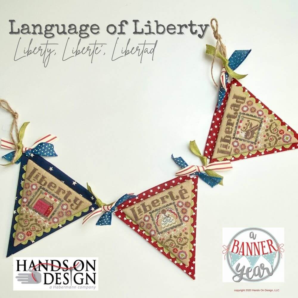 Finished cross stitch embroidery kit depicting the phrase 'Liberty, Liberte, Libertad' in a decorative pattern with red, white, and blue colors on a white background 'Hands On Design'.
[image_link]