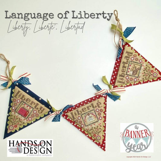 Finished cross stitch embroidery kit depicting the phrase 'Liberty, Liberte, Libertad' in a decorative pattern with red, white, and blue colors on a white background 'Hands On Design'.
[image_link]