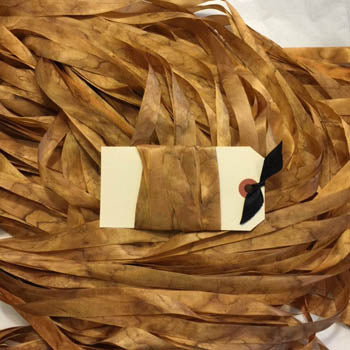 A brown, grubby jack rayon ribbon trim with a tag showing the brand name and a small design sample.
[image_link]