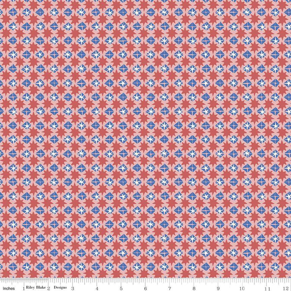 A close-up of a repeating fabric pattern with coral red, light blue, and white geometric medallions, shown with a ruler along the bottom edge for scale.
Photo by RileyBlakeDesigns.com [image_link]