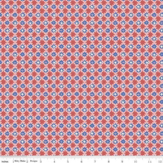 A close-up of a repeating fabric pattern with coral red, light blue, and white geometric medallions, shown with a ruler along the bottom edge for scale.
Photo by RileyBlakeDesigns.com [image_link]