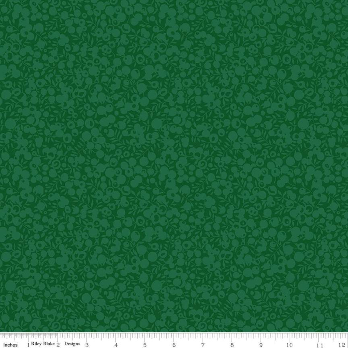A close-up fabric or material swatch in dark green with a repeating tonal floral or paisley-like pattern. A white measurement ruler runs along the bottom edge, showing scale.
Photo by RileyBlakeDesigns.com [image_link]