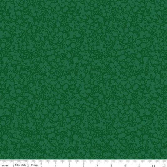 A close-up fabric or material swatch in dark green with a repeating tonal floral or paisley-like pattern. A white measurement ruler runs along the bottom edge, showing scale.
Photo by RileyBlakeDesigns.com [image_link]