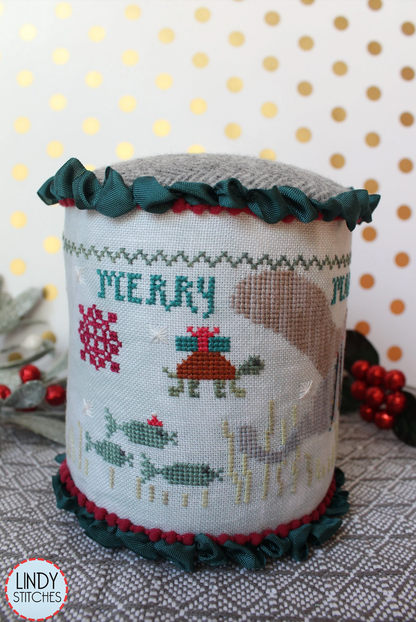 A cross stitch pattern drum kit depicting manatees in a Christmas theme, with holiday decorations and a Santa hat, from Lindy Stitches.
Photo by Lindy Stitches [additional_image_link]