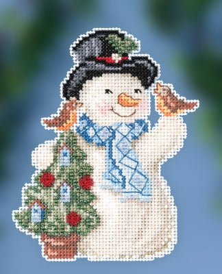 Snowman with a carrot nose, top hat, and scarf holding a Christmas tree on a white background.
Photo by Mill Hill [image_link]