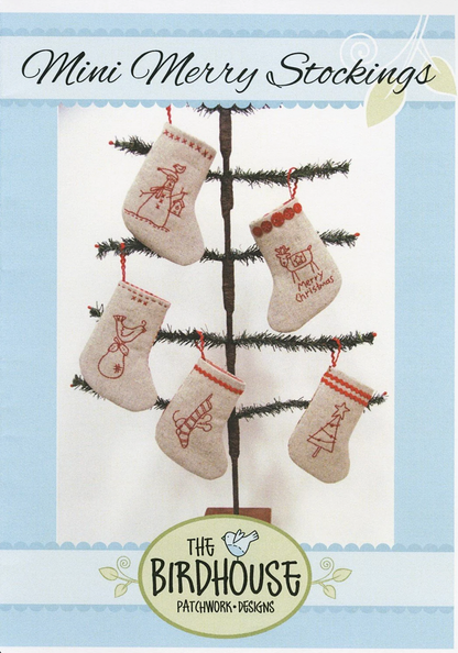 Pattern cover for 'Mini Merry Stockings' by The Birdhouse Patchwork & Designs, showing five beige embroidered Christmas stockings hanging on a small tree against a light blue and white background.
Photo by The Birdhouse Patchwork Designs [image_link]
