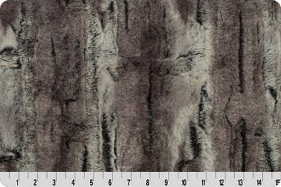 A close-up of faux fur fabric with a mottled gray, brown, and black pattern, shown with a white ruler at the bottom indicating scale.
Photo by Shannon Fabrics [additional_image_link]