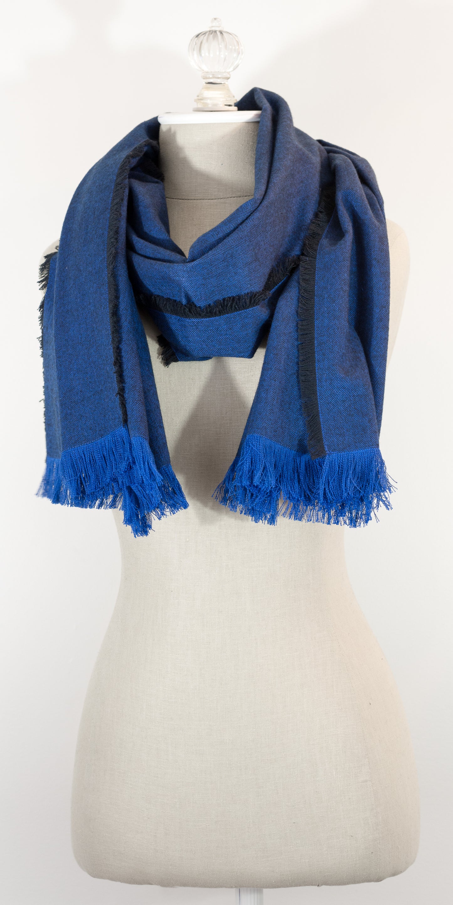 Navy blue herringbone flannel blanket scarf displayed on a mannequin, with fringe detailing and a kilt pin.
Photo by Karen King  [additional_image_link]