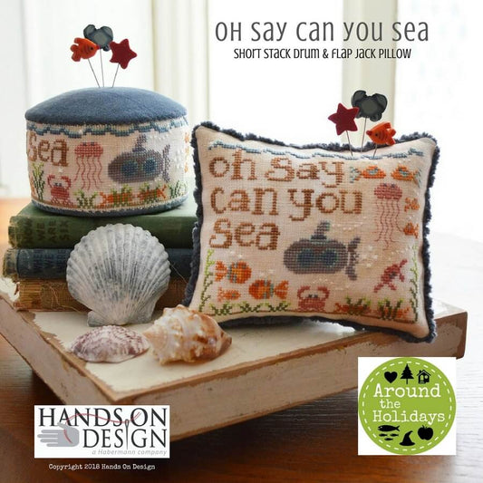Two cross-stitch embroidery pillows with the phrases 'Oh say can you sea' and 'Sea friends' on a table, along with a stack of books, a shell, and some decorative items.
[image_link]