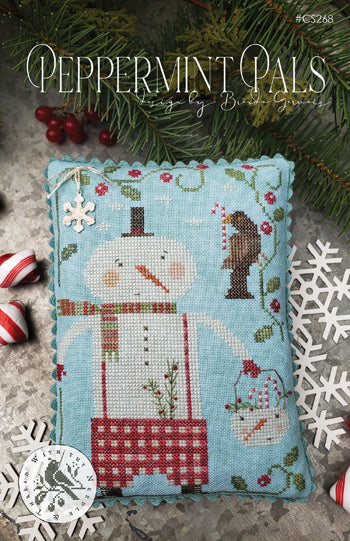 A square cross-stitch sampler featuring a snowman and bird design on a light blue background, surrounded by holiday decorations including pine branches, red berries, candy canes, white snowflake cutouts, and a circular silver ornament. The text 'Peppermint Pals' appears at the top.
Photo by With Thy Needle & Thread [image_link]