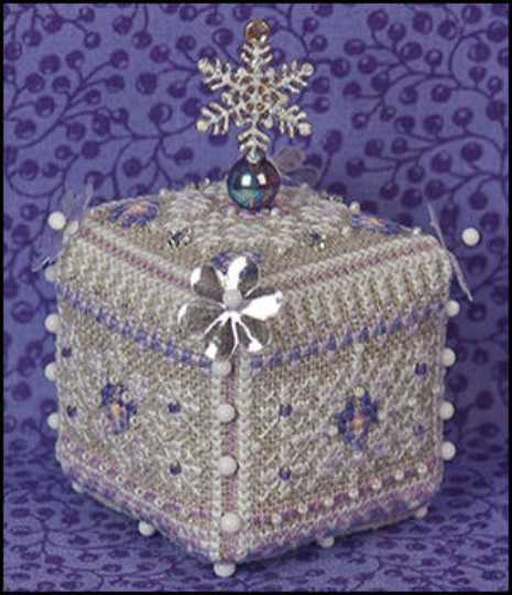 A cross-stitch embroidery kit cube ornament designed with a pansy flower with a white, silver, and purple color scheme, adorned with beads and pearls on a textured linen background.
Photo by JustNan.com [image_link]