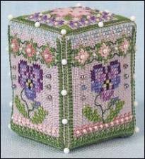 A square cross-stitch cube box decorated with purple flowers, green leaves, and pink and purple floral patterns on a light background.
Photo by JustNan.com [additional_image_link]
