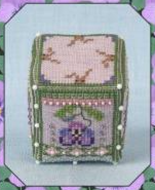A small decorative cube featuring a floral design with green borders, pink top section, and purple flower motif, shown against a pale blue background with a purple patterned border.
Photo by JustNan.com [additional_image_link]