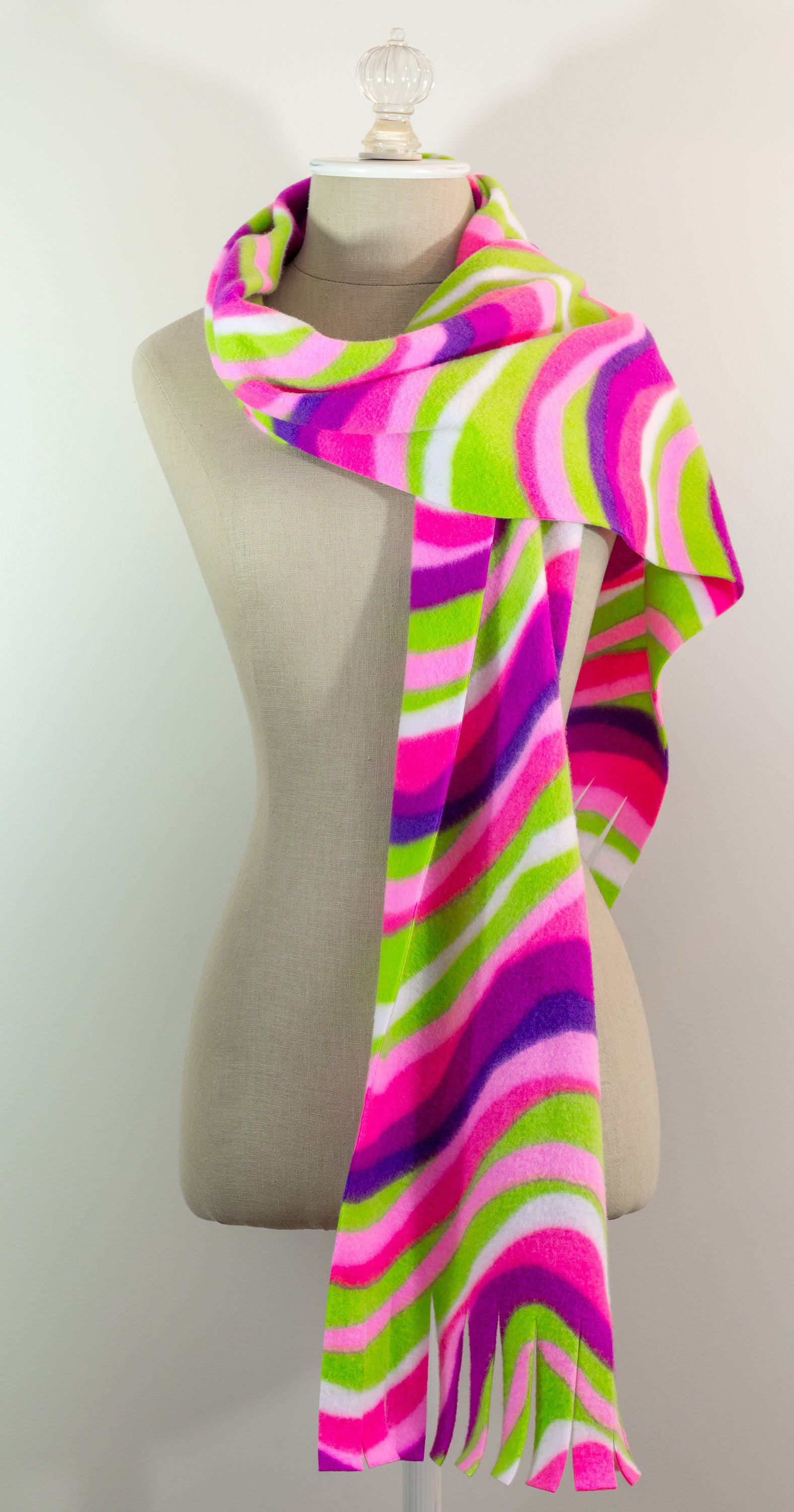 A scarf with a striped pattern featuring pink, green, white, and purple colors, displayed on a mannequin.
Photo by The Surgeon's Knots [additional_image_link]