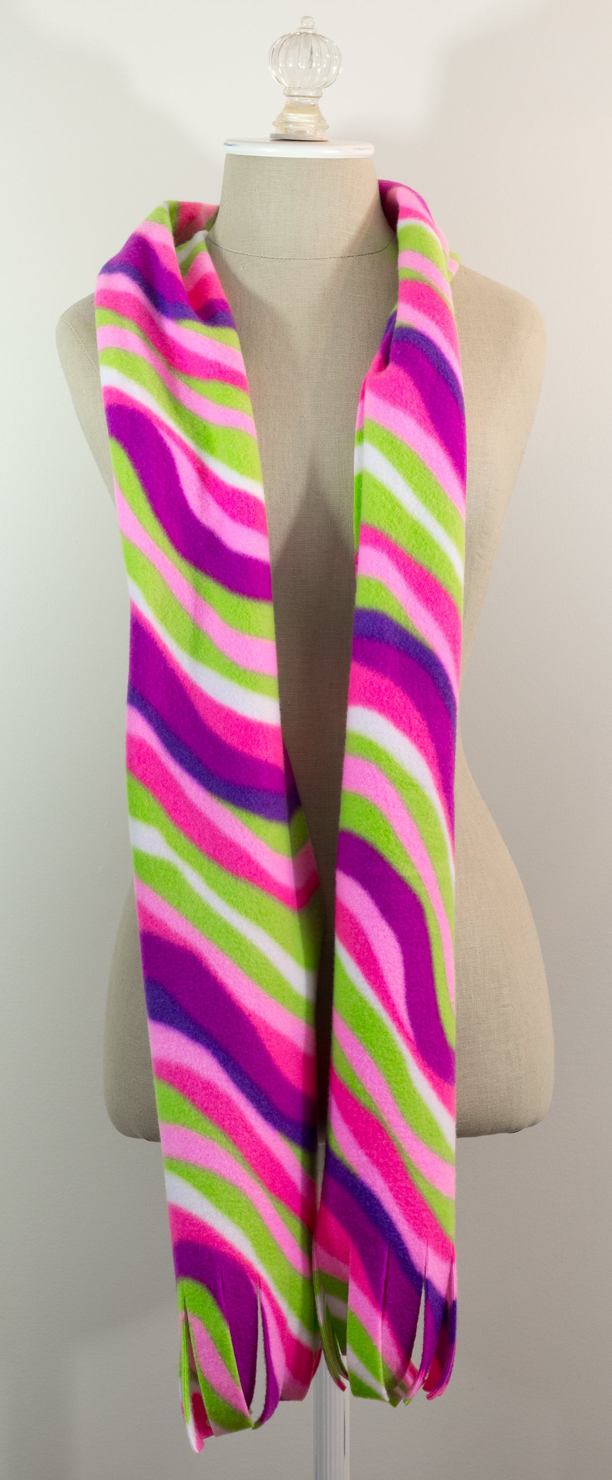 A scarf with a striped pattern featuring pink, green, white, and purple colors, displayed on a mannequin.
Photo by The Surgeon's Knots [additional_image_link]