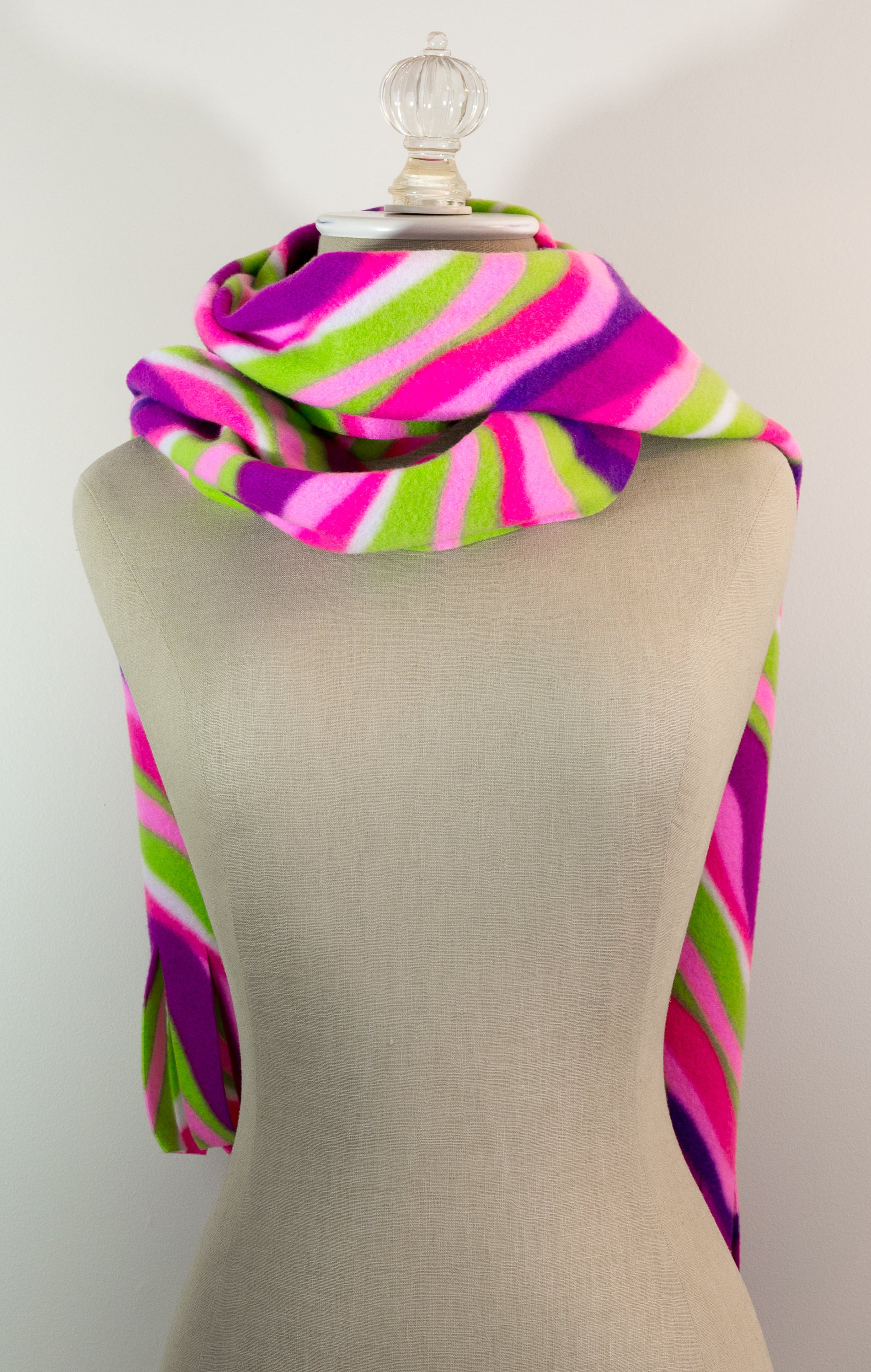 A scarf with a striped pattern featuring pink, green, white, and purple colors, displayed on a mannequin.
Photo by The Surgeon's Knots [additional_image_link]
