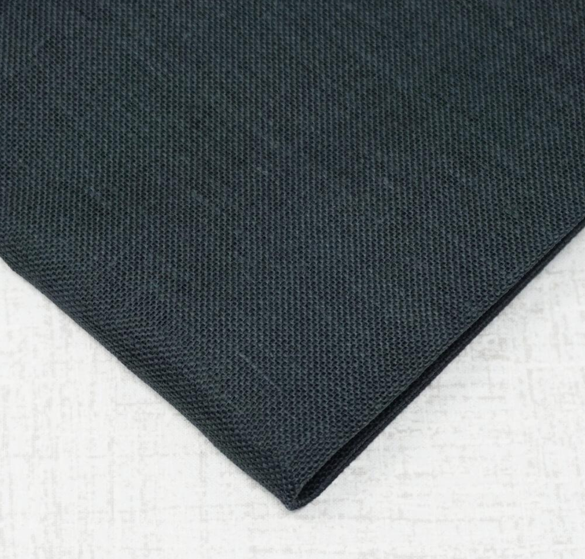 A close-up of folded dark charcoal gray fabric with a textured weave, placed on a light gray surface.
Photo by Wichelt.com [additional_image_link]