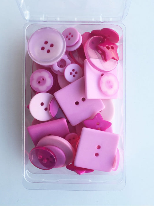A clear plastic container holding 55 handmade pink buttons of various shapes and sizes, ranging from 1/4 inch to 1-1/8 inch, with a pink star design on some of them.
Photo by JustAnotherButtonCompany.com [image_link]