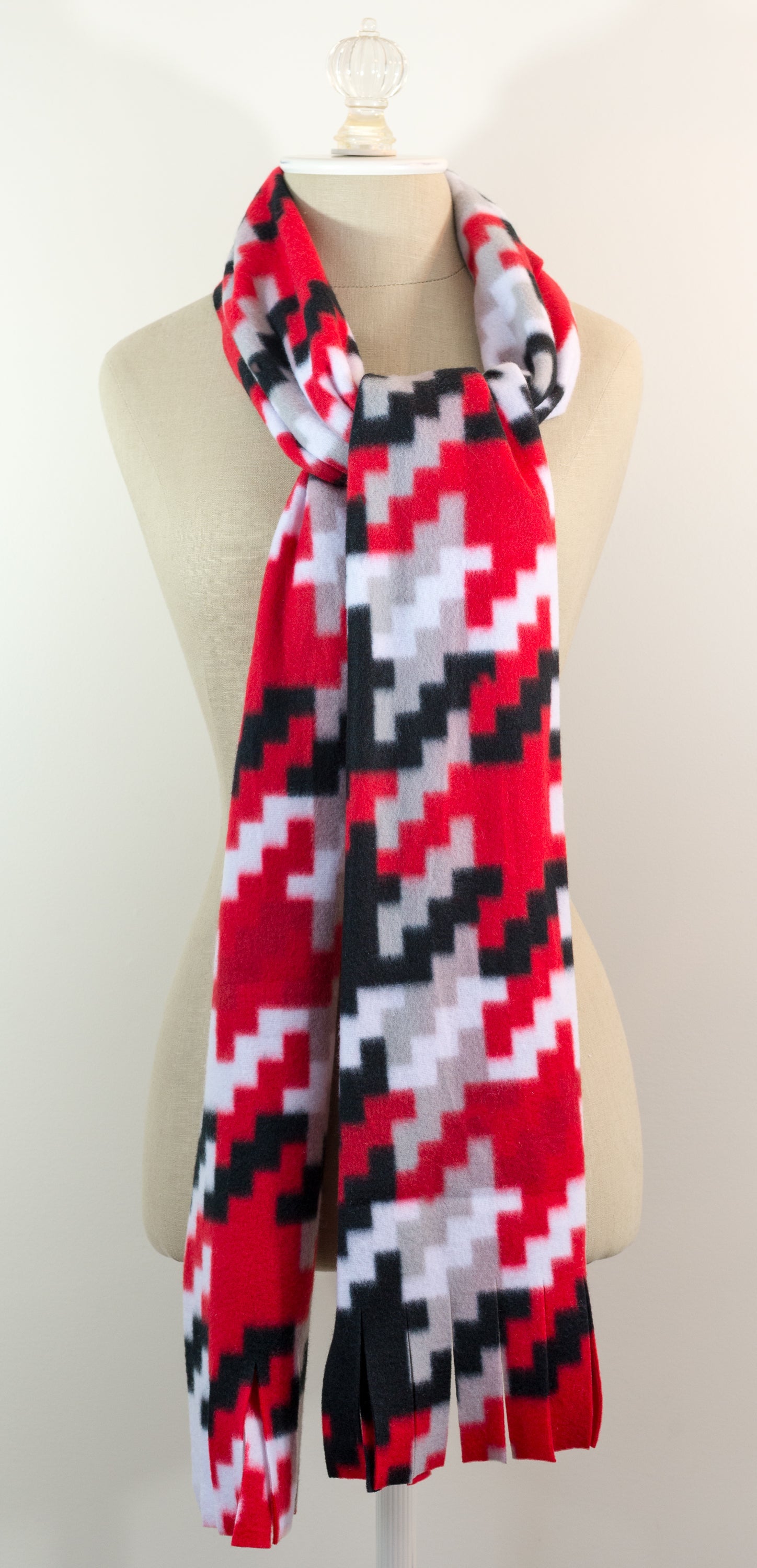 A scarf with a geometric houndstooth pattern in shades of red, white and black, displayed on a mannequin.
Photo by Karen King [additional_image_link]