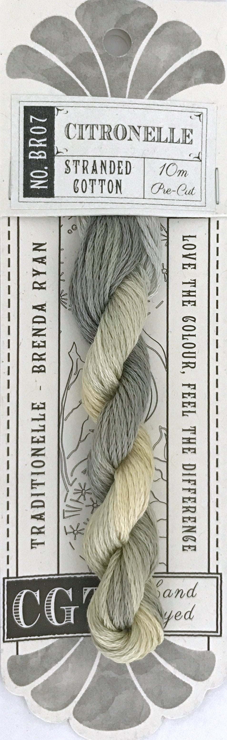 A skein of Citronelle stranded cotton embroidery thread by Brenda Ryan, featuring a pale variegated color shift from gray-green to cream, mounted on its original printed cardboard packaging.
Photo by cottagegardenthread.com [additional_image_link]