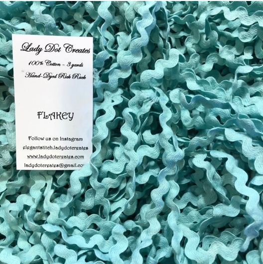 A close-up of teal green ric rac piled together, with a white paper label on the left reading 'Lady Dot Creates' and 'FLAKEY'.
Photo by LadyDotCreates.biz [additional_image_link]
