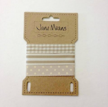 A spool of Jane Means ribbon in a natural kraft paper packaging, featuring three patterned ribbons: a beige and white gingham, a beige and white stripe pattern, and a cream polka dot pattern on a white background.
Photo by Jane Means [additional_image_link]
