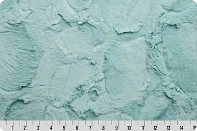 A close-up of a textured fabric or material swatch in a pale minty aqua color, with a white ruler along the bottom edge showing measurements.
Photo by Shannon Fabrics [additional_image_link]
