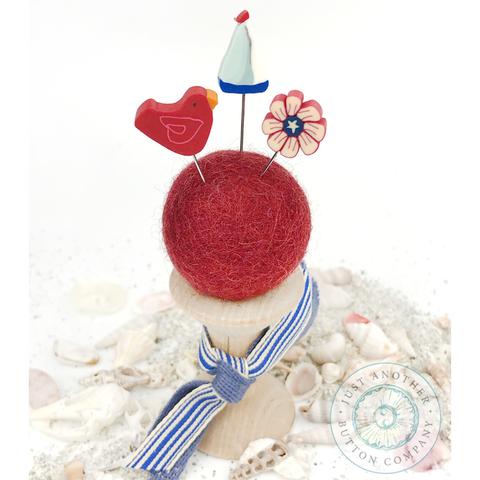 A pincushion kit from Just Another Button Company, featuring a red felted wool ball, a wooden spool, and two seaworthy ribbons.
Photo by JustAnotherButtonCompany.com [additional_image_link]