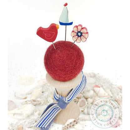 A pincushion kit from Just Another Button Company, featuring a red felted wool ball, a wooden spool, and two seaworthy ribbons.
Photo by JustAnotherButtonCompany.com [additional_image_link]