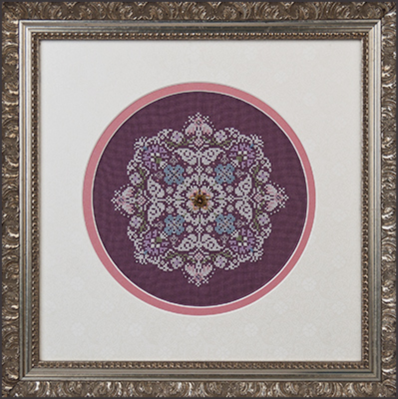 A framed cross stitch embroidery kit depicting a snowflake pattern with purple, blue, and green colors, encased in a decorative frame.
Photo by JustNan.com [image_link]